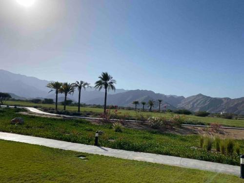 a park with palm trees and mountains in the background at Lovely studio apartment inside Jebel Sifah resort in As Sīfah