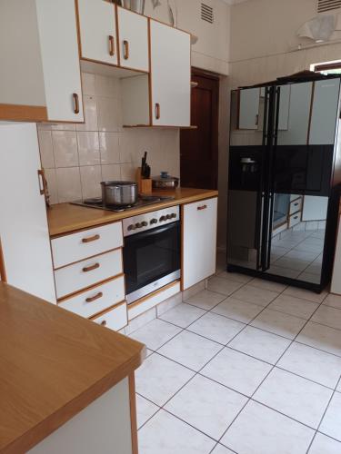 a kitchen with white cabinets and a black refrigerator at Margate Accomodation in Margate