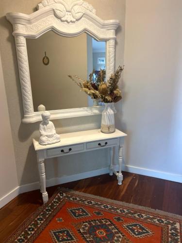 a dressing table with a mirror and a vase on it at Koombana Retreat in Perth