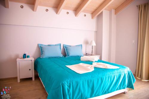 a bedroom with a blue bed with blue pillows at Liberte Maisonettes in Parga