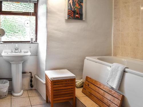 a bathroom with a bath tub and a sink at Church House Cottage in Ulpha