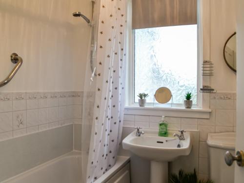 a bathroom with a sink and a shower curtain at Muirston Farmhouse in Ochiltree