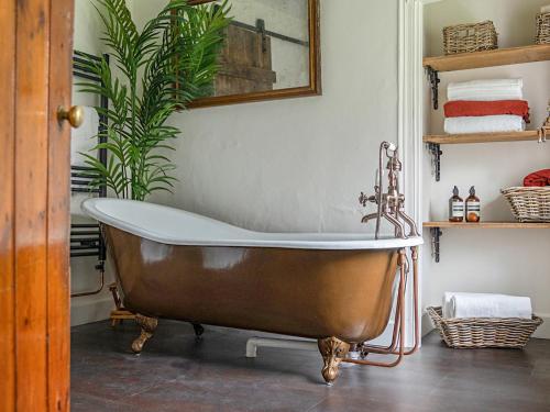 una bañera antigua en un baño con una planta en Thorn Cottage, en Winsford