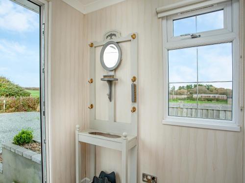 a small bathroom with a mirror and a window at Red Post Lodge in Bridgerule