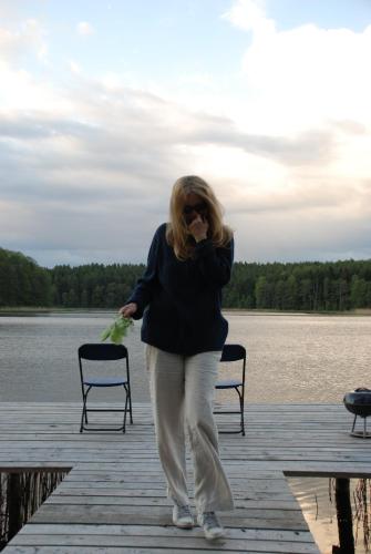 a woman walking on a dock talking on a cell phone at Natura Apartamenty in Swaderki
