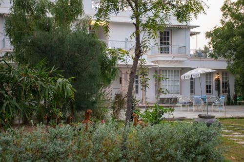 a white house with a table and chairs in a garden at Naila Kothi - A Luxury Boutique Royal Suites in Jaipur in Jaipur