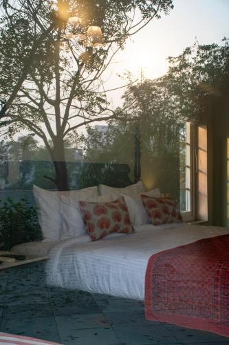 a large bed with pillows in a room with a tree at Naila Kothi - A Luxury Boutique Royal Suites in Jaipur in Jaipur