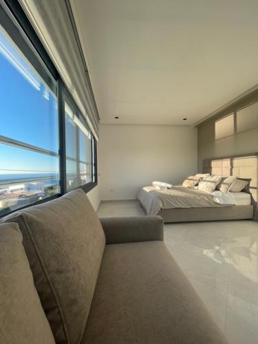 two beds in a room with a couch and a window at Villa Eleonor in Tangier