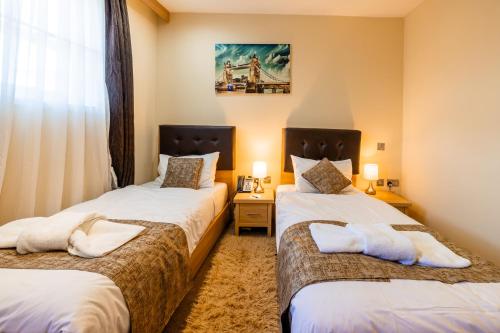 two twin beds in a room with a window at The Shoreditch Inn in London