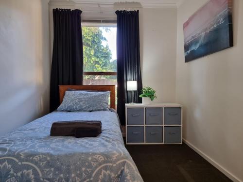 a bedroom with a bed with a blue comforter and a window at 4bed 2bath house 5 mins walk to Palms & Golf club in Christchurch