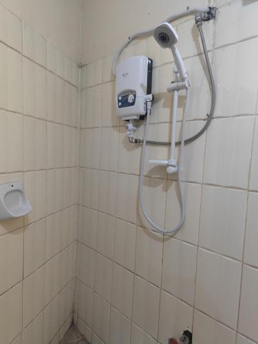 a shower in a white tiled bathroom at Pentacasa in Jinja