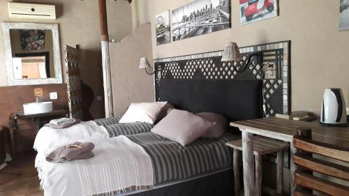 a bedroom with two beds and a table and a desk at African Silhouette Guesthouse in Benoni
