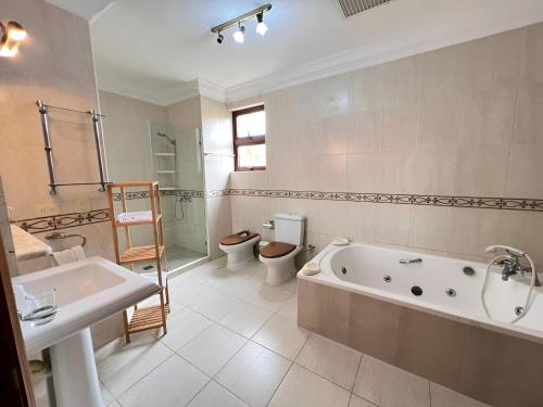 Un baño con bañera, inodoro y lavabo. en Metro Golf Villa, en Paraíso