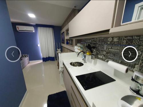 una cocina con encimeras blancas y fregadero. en Hotel Samba Cabo Frio Flat en Cabo Frío