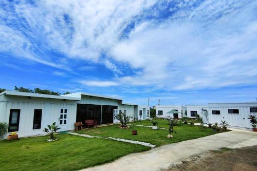 a row of white buildings with a grass yard at Second Hostel in Xiaoliuqiu
