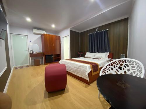 Bạc LiêuにあるMotel Happy Houseのベッドと椅子付きのホテルルーム