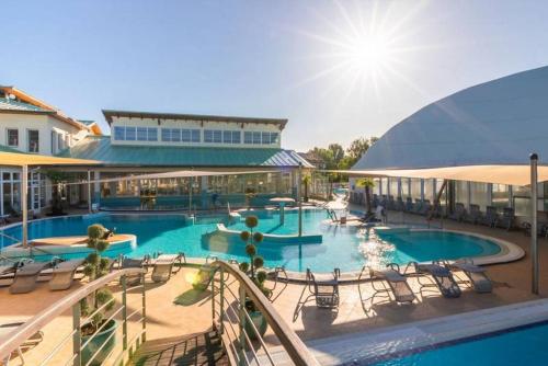 a large swimming pool with chairs and a building at Safit-Mandala in Mosonmagyaróvár