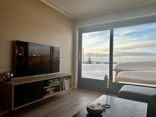 uma sala de estar com televisão e uma grande janela em Lys og moderne leilighet rett ved skiløypa på Nordseter - Kort vei til Sjusjøen, Lillehammer og Hafjell - Dyr ikke tillatt em Nordseter