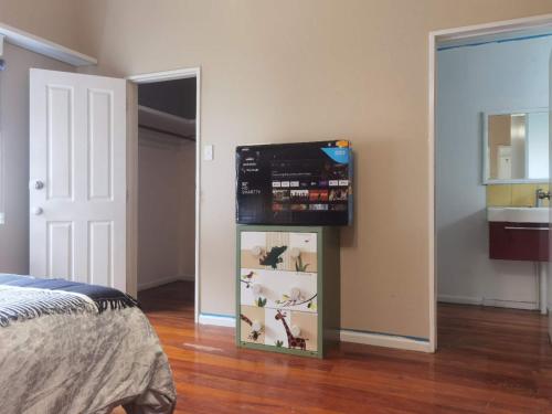 1 dormitorio con TV en la parte superior de un estante en Mt Eden Master Suite RM1, en Auckland