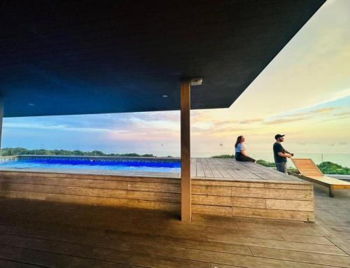 two people standing on a wooden boardwalk near a body of water at Umhlangha Oceans Dunes in Umhlanga