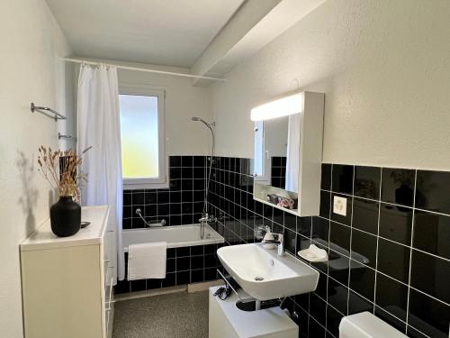 a black and white bathroom with a sink and a tub at Gemütliche Wohnung Nähe Uni in Basel
