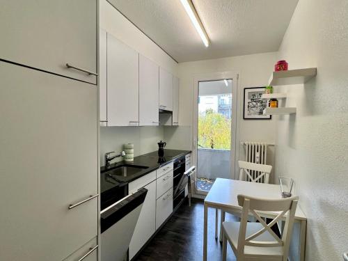 uma cozinha com armários brancos, uma mesa e uma sala de jantar em Gemütliche Wohnung Nähe Uni em Basileia