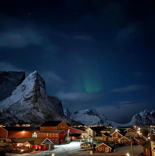 a town with a green northern light in the sky at night at Reinebua in Reine