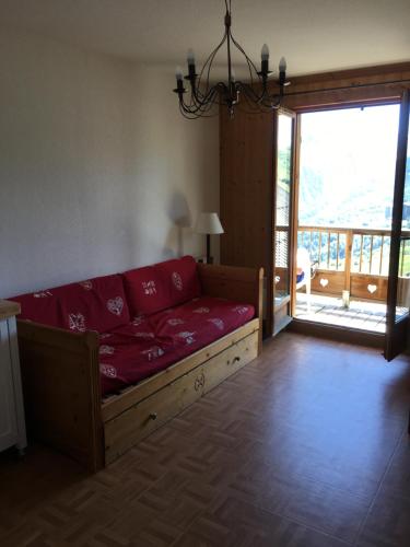 un salon avec un canapé rouge et un balcon dans l'établissement Chalet des cimes, à La Toussuire