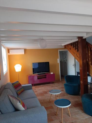 a living room with a couch and a tv at Gite climatisé L'Orée des Landes Proche Center Parcs in Pindères