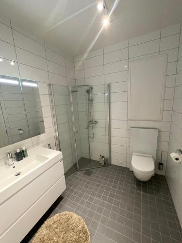 a white bathroom with a toilet and a sink at Cosy and centrally located apartment in Tromsø