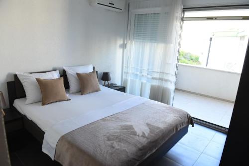 a bedroom with a large white bed with a window at Apartmani Sutomore Tri Palme in Sutomore