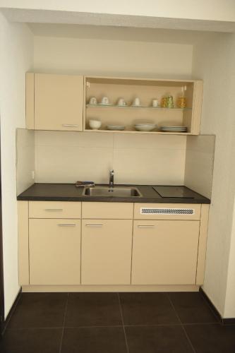 a kitchen with white cabinets and a sink at Apartmani Sutomore Tri Palme in Sutomore
