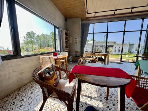 een woonkamer met een tafel, stoelen en ramen bij Second Hostel in Xiaoliuqiu