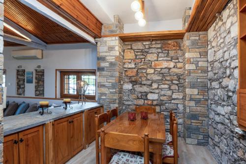 cocina con mesa de madera y pared de piedra en The Sea Front Fisherman’s house, en Kato Gatzea