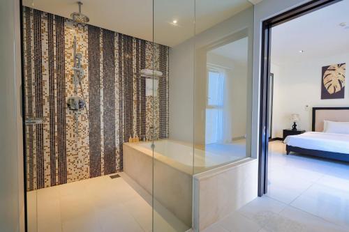 a bathroom with a glass shower and a bed at The Sea Luxury Nha Trang Apartment in Nha Trang