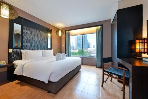 een slaapkamer met een groot wit bed en een bureau bij Royal View Resort - Rang Nam in Bangkok