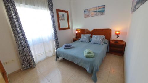 a bedroom with a bed with blue sheets and a window at Rico Apartaments Ricosol in Torrox Costa