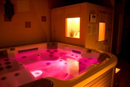 uma grande banheira de hidromassagem com iluminação rosa na casa de banho em La Erilla em Braojos de la Sierra