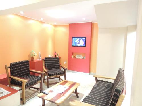 a waiting room with chairs and a tv on a wall at Hotel Buenos Aires in Salta