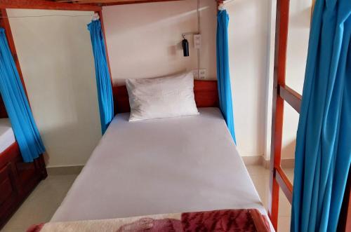 a bunk bed in a small room with blue curtains at Cam Ly Homestay in Da Lat