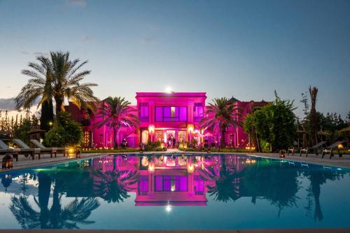 uma casa cor-de-rosa com uma piscina em frente em Nomadz Palace em Marraquexe