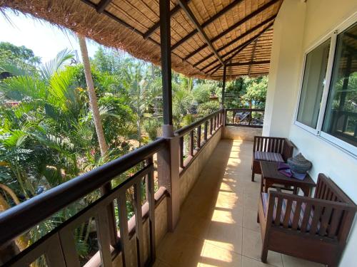 einen Balkon eines Hauses mit einem Tisch und Bänken in der Unterkunft Good Time Sports Village Koh Mak in Ko Mak
