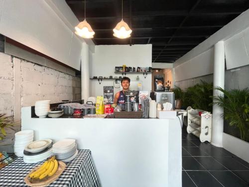 a man standing behind a counter with plates and bananas at MOOK BOONCHU HOTEL in Koh Mook