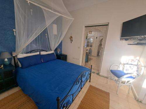 um quarto com uma cama de dossel azul em Villa La Palmeraie em Oualidia