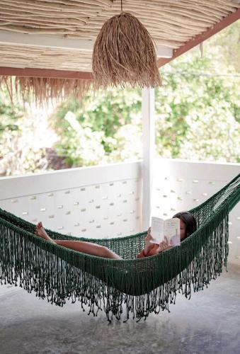 a woman laying in a hammock reading a book at Hacienda Villa Watukarung in Watukarung
