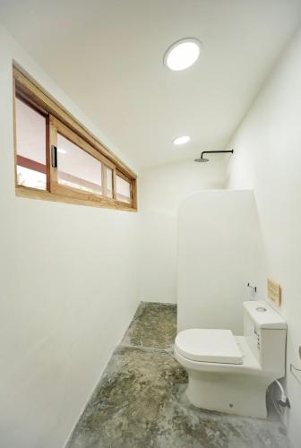 a white bathroom with a toilet and a window at Hacienda Villa Watukarung in Watukarung