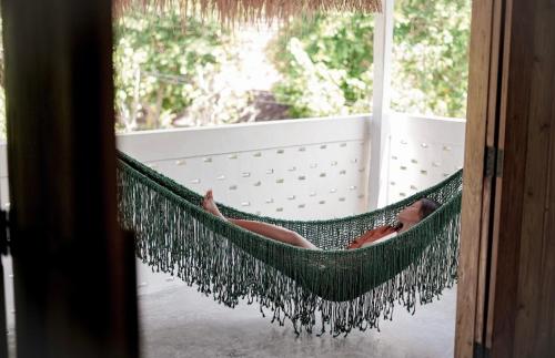 a woman laying in a hammock on a porch at Hacienda Villa Watukarung in Watukarung
