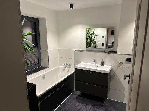 a bathroom with a sink and a tub and a mirror at Marleens Ferienwohnung in Schwerin in Schwerin