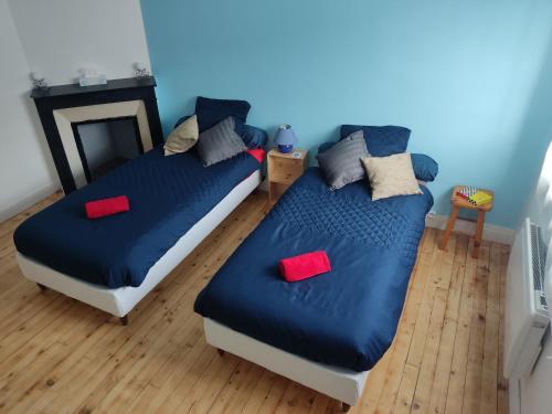 um quarto com 2 camas com lençóis azuis e almofadas vermelhas em La Saint Quentinoise (avec cour) em Saint-Quentin
