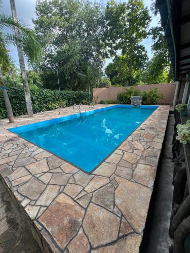 una piscina con un patio de piedra y agua azul en TEMBO Cottage Wilpattu, en Wilpattu